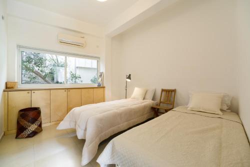 two beds in a white room with a window at Relax & Sunny near Beach by FeelHome in Tel Aviv