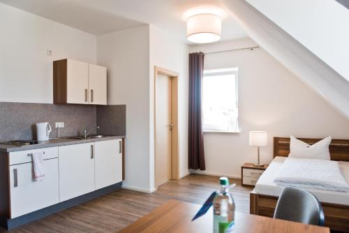 Zimmer mit einem Bett und einer Küche mit einem Tisch in der Unterkunft greenpartment Boardinghouse Neustadt in Neustadt an der Donau
