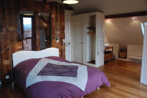 EpfigにあるGites Les Petits Tisserandsのベッドルーム(紫の毛布を使用した大型ベッド1台付)