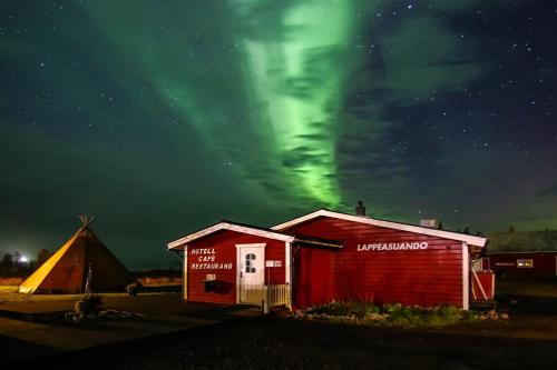 a couple of buildings with the aurora in the sky at Lappeasuando Lodge in Puoltikasvaara