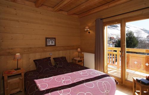 une chambre avec un lit et une grande fenêtre dans l'établissement Odalys Chalet Levanna Occidentale, à Les Deux Alpes