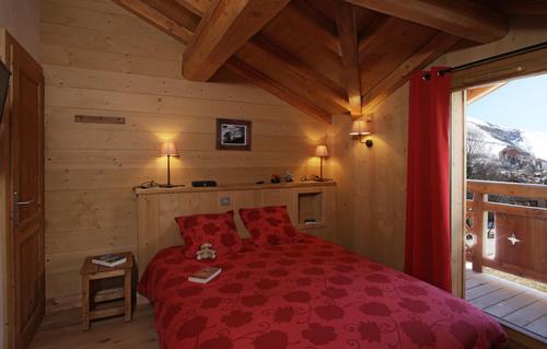 レ・デュー・アルプにあるOdalys Chalet Levanna Occidentaleのキャビン内の赤いベッド1台が備わるベッドルーム1室を利用します。