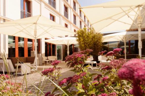 a patio with white umbrellas and flowers in front of a building at A-ROSA Sylt in List