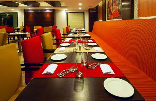 a long table in a restaurant with red chairs at The Golden Plaza Hotel in Chandīgarh
