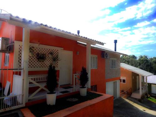 una casa rossa con due piante in vaso davanti di Glamour Gramado Residence a Gramado