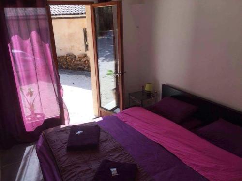 - une chambre avec un lit doté de draps violets et une fenêtre dans l'établissement Studio dans les bois, à Blésignac