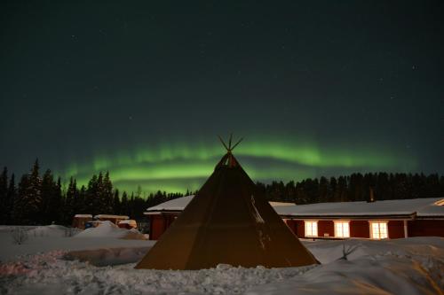 an igloo with the aurora in the sky at Lappeasuando Lodge in Puoltikasvaara