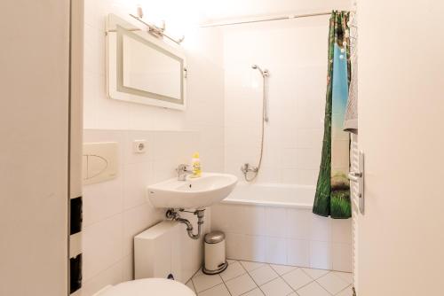 a bathroom with a sink and a toilet and a tub at Downtown Apartments Unterbilk in Düsseldorf