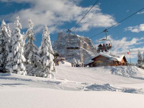 a ski lift with people on it in the snow at Villa Edelweiss in Alleghe