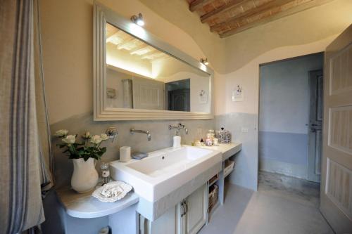 La salle de bains est pourvue d'un lavabo blanc et d'un miroir. dans l'établissement La casa di Arianna, à Casole dʼElsa