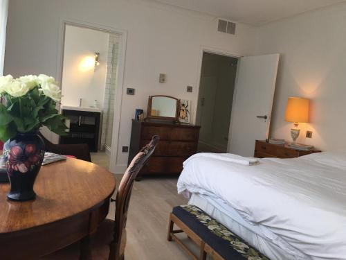 a bedroom with a bed and a table with a vase of flowers at Private luxury retreat in Sible Hedingham