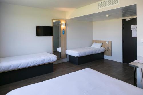 a hotel room with two beds and a tv at B&B HOTEL Bordeaux Est 3 étoiles in Tresses