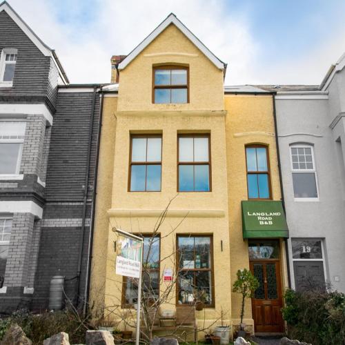 a yellow building with a green sign in front of it at Langland Road B&B in The Mumbles