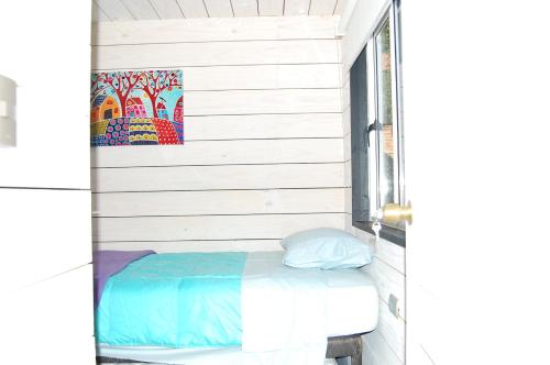 a bed sitting in a room next to a window at Cabaña del Bosque in Pichilemu