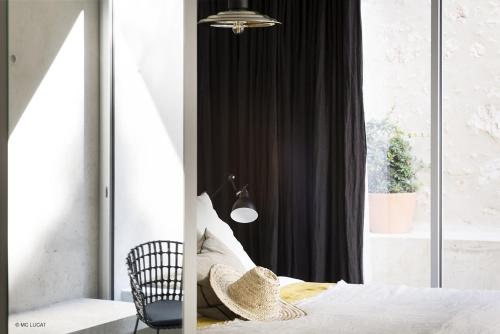 a bedroom with a bed with a chair and a window at Le 19-21 - Un amour d'hotel in Leucate