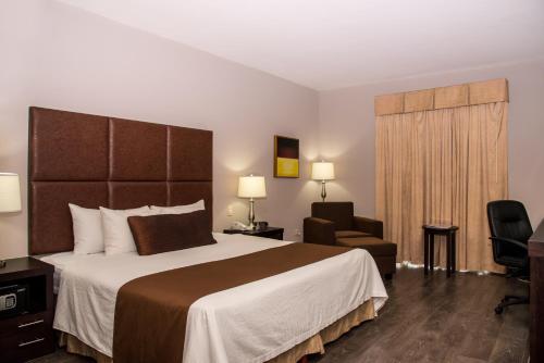 a hotel room with a bed and a chair at Best Western PLUS Monterrey Airport in Monterrey