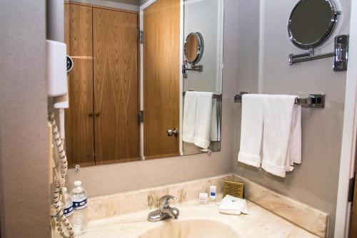 a bathroom with a sink and a mirror and towels at Best Western PLUS Monterrey Airport in Monterrey