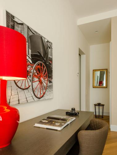 a table with a red lamp and a picture of a carriage at Roosevelt Stadthaus in Vienna