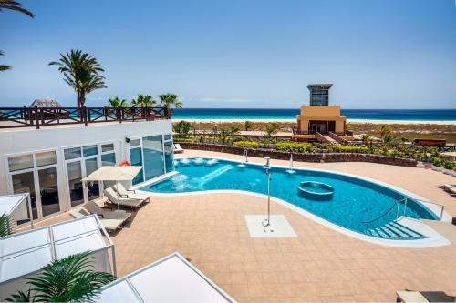 a swimming pool with the ocean in the background at Occidental Jandía Playa in Morro del Jable