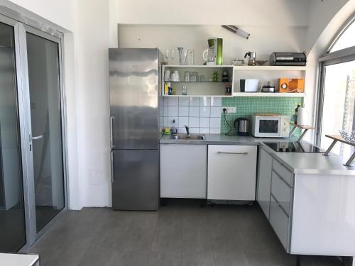 a kitchen with white cabinets and a stainless steel refrigerator at LOFT-Beach-apartments RATKO in Novi Vinodolski