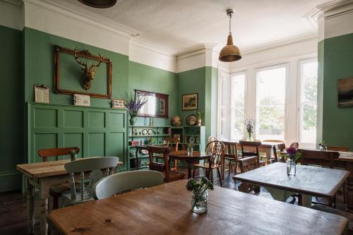 a restaurant with green walls and tables and chairs at The Coach House in Derby