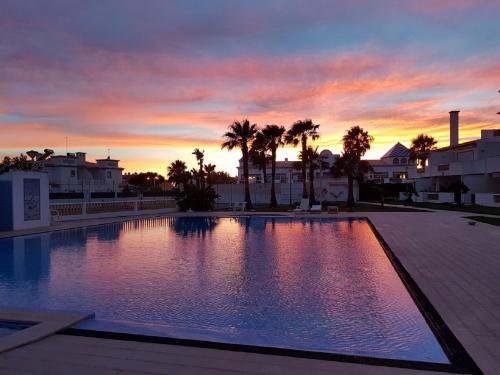 a large swimming pool with a sunset in the background at Moradia Galé in Guia
