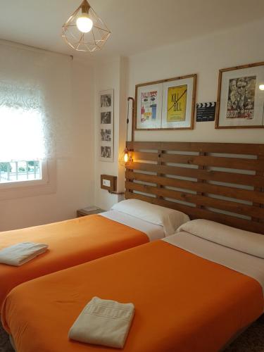 dwa łóżka w pokoju z pomarańczową pościelą w obiekcie Barri Antic Hostel & Pub w Andorze