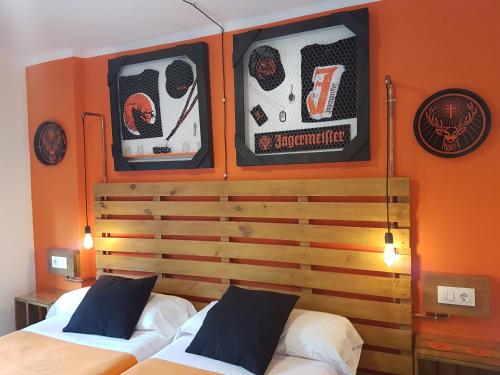 two beds in a room with orange walls at Barri Antic Hostel & Pub in Andorra la Vella