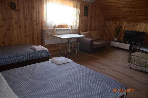 a room with a bed and a table and a television at Country House v Kleynikah in Brest