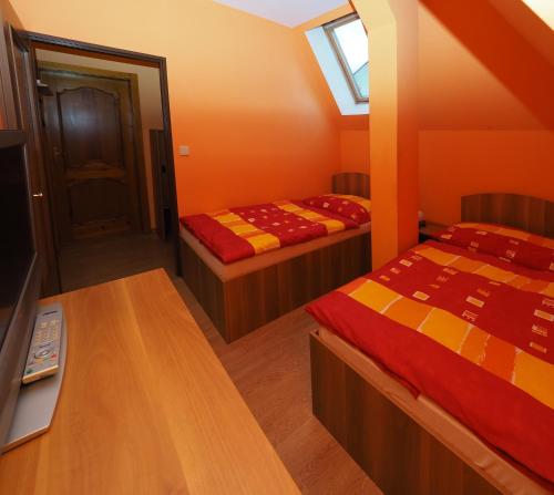 Dolní PoustevnaにあるPenzion U Krejzůのベッド2台とテーブルが備わる小さな客室です。