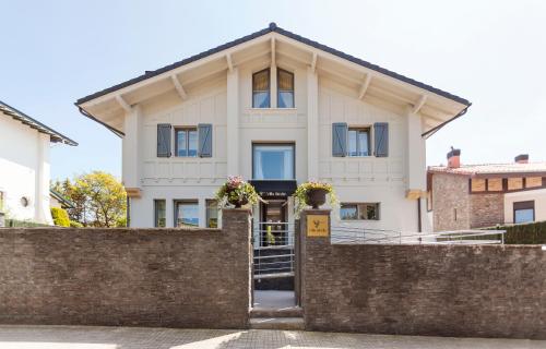 a white house with blue windows and a brick fence at Villa Birdie Boutique - Adults Only in Donostia-San Sebastián
