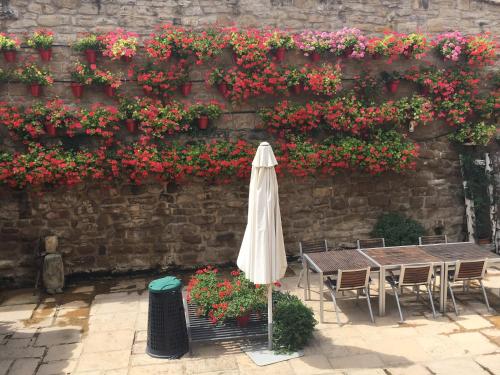 a table and umbrella next to a wall with flowers at La Pata de Oca Hostal Rural y Albergue in Torres del Río
