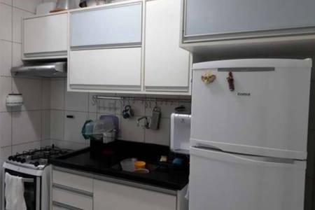  La cuisine est équipée de placards blancs et d'un réfrigérateur. dans l'établissement Apartamento 2 Quartos vista mar, à Salvador