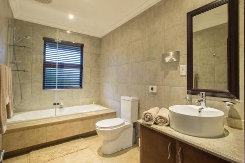 a bathroom with a sink and a toilet and a tub at Zimbali Holiday Home-22 Acaciawood in Ballito