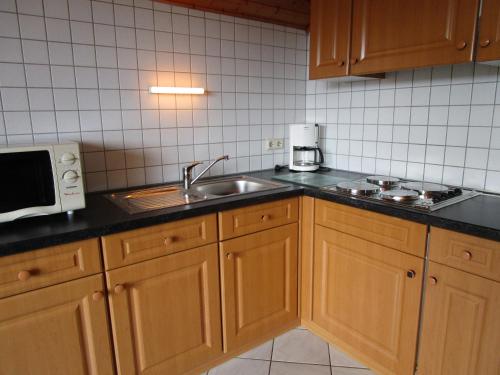 a kitchen with wooden cabinets and a sink at Ferienwohnungen am Wald in Lieser