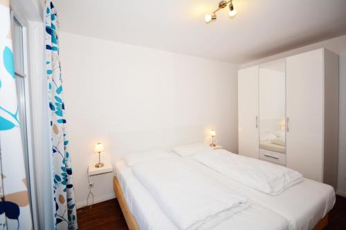 um quarto com uma cama branca e um espelho em Komfort-Ferienwohnung Rosa Nr. 6 by Meer-Ferienwohnungen em Ostseebad Sellin