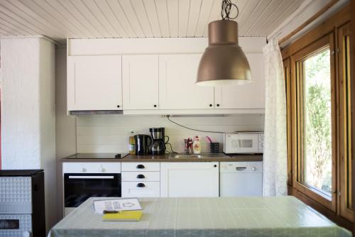 a kitchen with white cabinets and a table with a lamp at Herrö stugor in Lemland