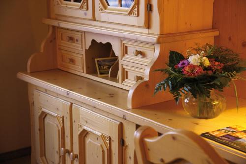 a wooden cabinet with a vase of flowers on a table at Hotel Omesberg in Lech am Arlberg
