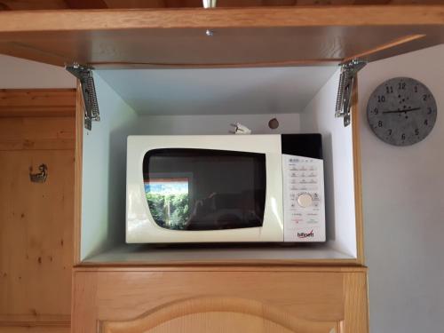 a microwave sitting on top of a cabinet with a clock at Haus Elisabeth in Napplach