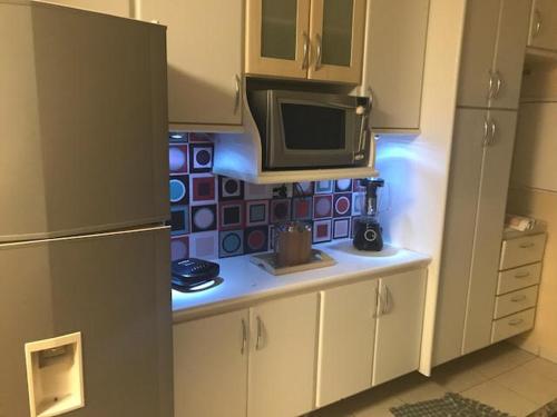 a kitchen with a counter with a microwave and a refrigerator at Charmoso Apartamento no Bairro Jardim in Santo André