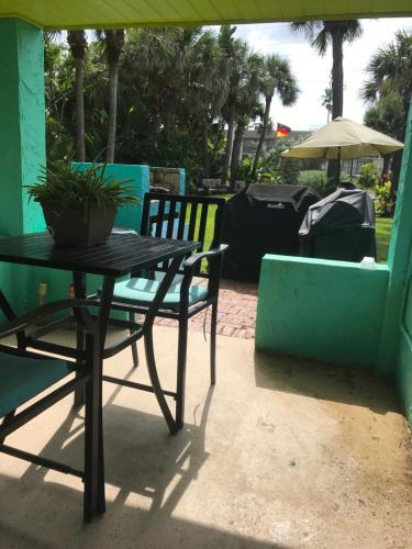 a table and a chair with a potted plant on a patio at South Beach Inn - Cocoa Beach in Cocoa Beach