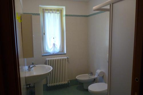 a bathroom with a sink and a toilet and a window at Nina & Berto in Verbania