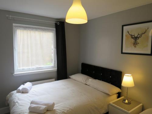 um quarto com uma cama branca com um candeeiro e uma janela em Our City - Gilmours Entry em Edinburgo