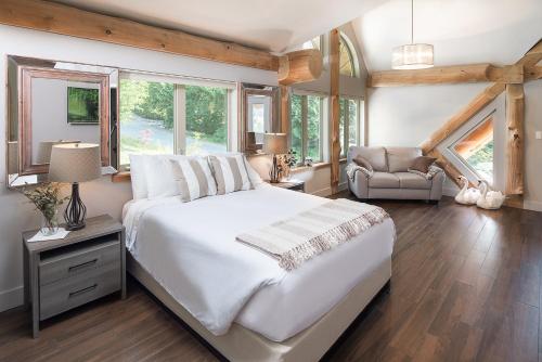 a bedroom with a large white bed and a chair at The Rockwell-Harrison Guest Lodge in Harrison Hot Springs
