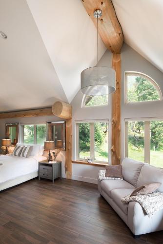a bedroom with a bed and a couch and windows at The Rockwell-Harrison Guest Lodge in Harrison Hot Springs