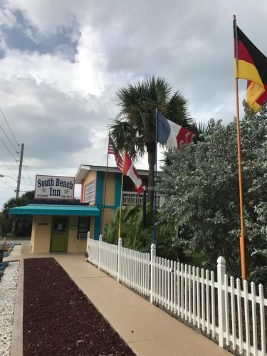 a white fence with flags in front of a building at South Beach Inn - Cocoa Beach in Cocoa Beach