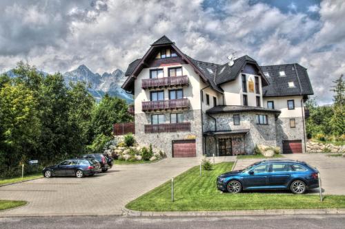 a large house with cars parked in a parking lot at Matrix in Tatranská Lomnica