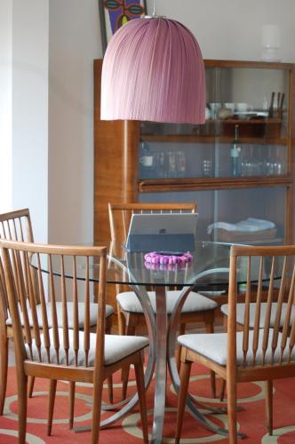una mesa de cristal con 2 sillas y una lámpara rosa en Casa Finisterre, en Puerto Pirámides