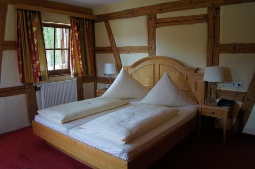 a bedroom with a large bed with a wooden headboard at Gasthof Schönau in Heilsbronn