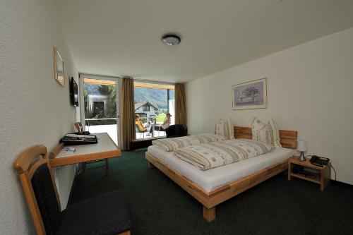 1 dormitorio con cama, escritorio y ventana en Hotel Hahnenblick en Engelberg